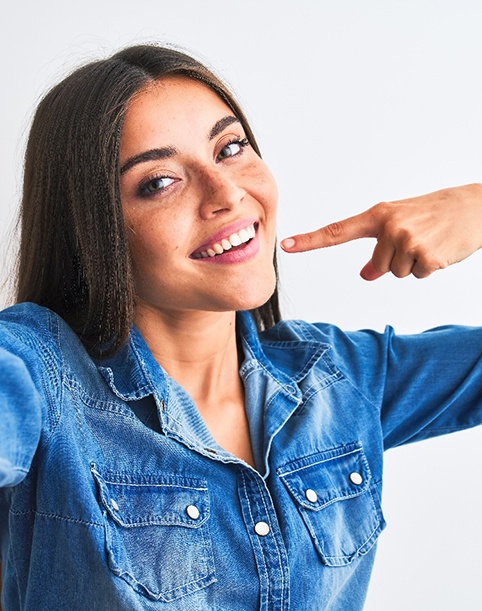 Smiling woman pointing to her white teeth