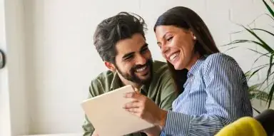 Smiling man and woman looking at a tablet