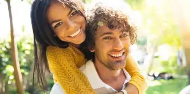 Smiling man carrying smiling woman on his back